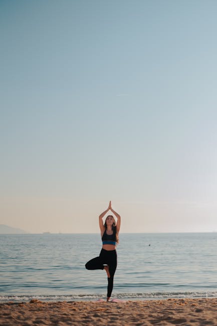Woman performing a serene yoga pose outdoors by the lake during sunrise.